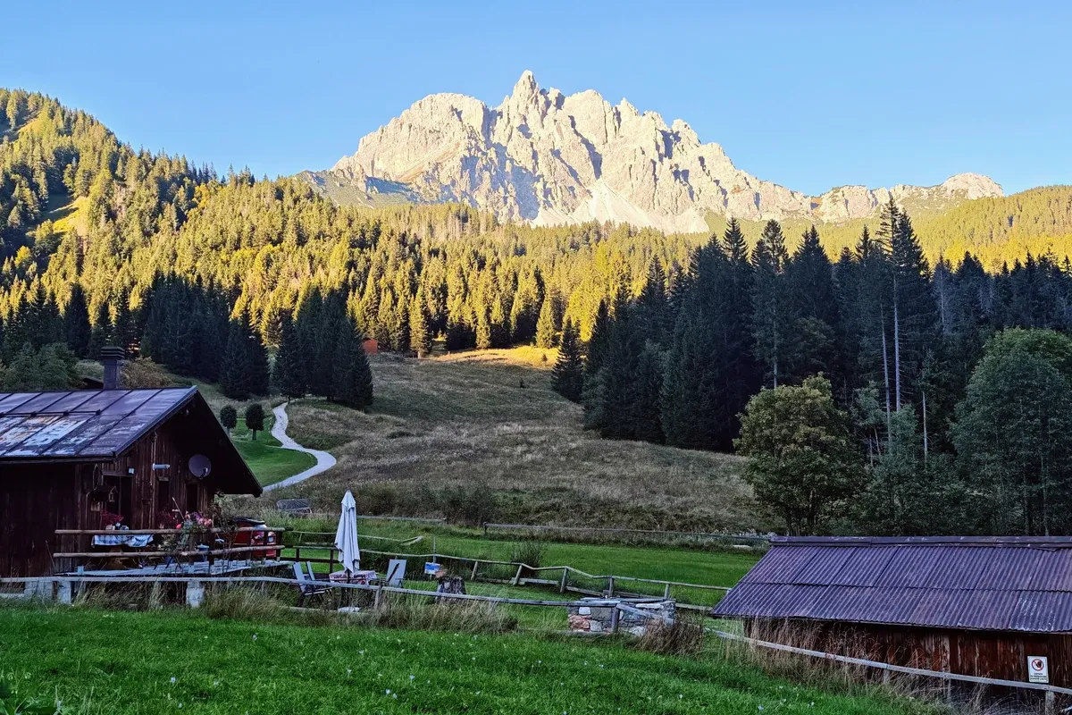 A luz dourada do fim de tarde banha Auronzo e destaca o reflexo das montanhas na água calma