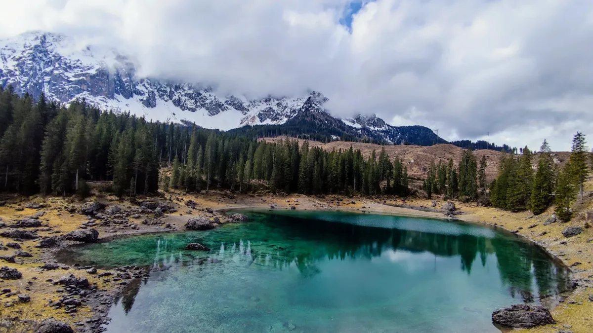 Estrada sinuosa de montanha nas Dolomitas italianas durante o outono com folhagem dourada e picos ao fundo.