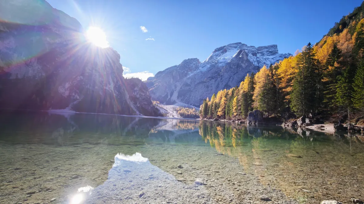 Vista panorâmica do Lago di Braies nas Dolomitas com água esmeralda, barcos de madeira e montanhas ao fundo no outono.